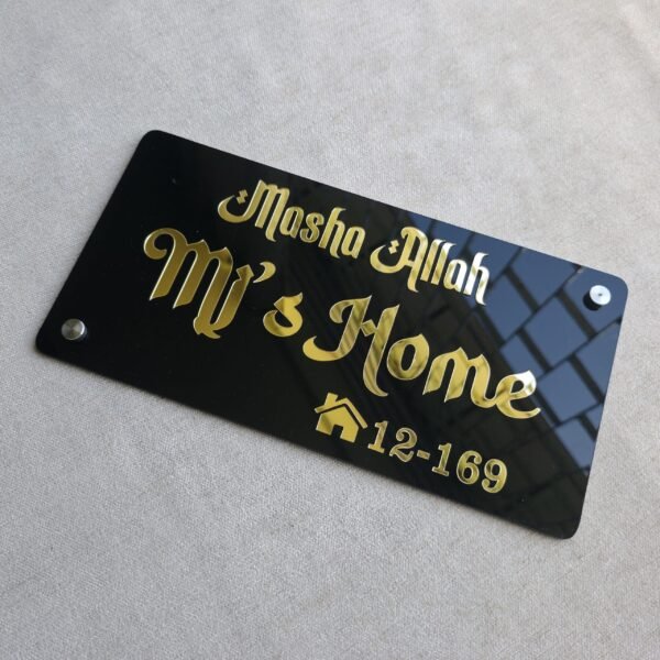 Top-down angled shot of the golden Mashallah nameplate with two silver mounting studs attached.
