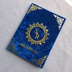 An angled perspective of the personalized royal blue velvet Nikah Nama booklet, showing the 3D effect of the gold acrylic lettering.