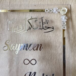 A close-up shot of the top right corner of the Nikah Thumb Board, highlighting the Arabic calligraphy and white floral embellishments.